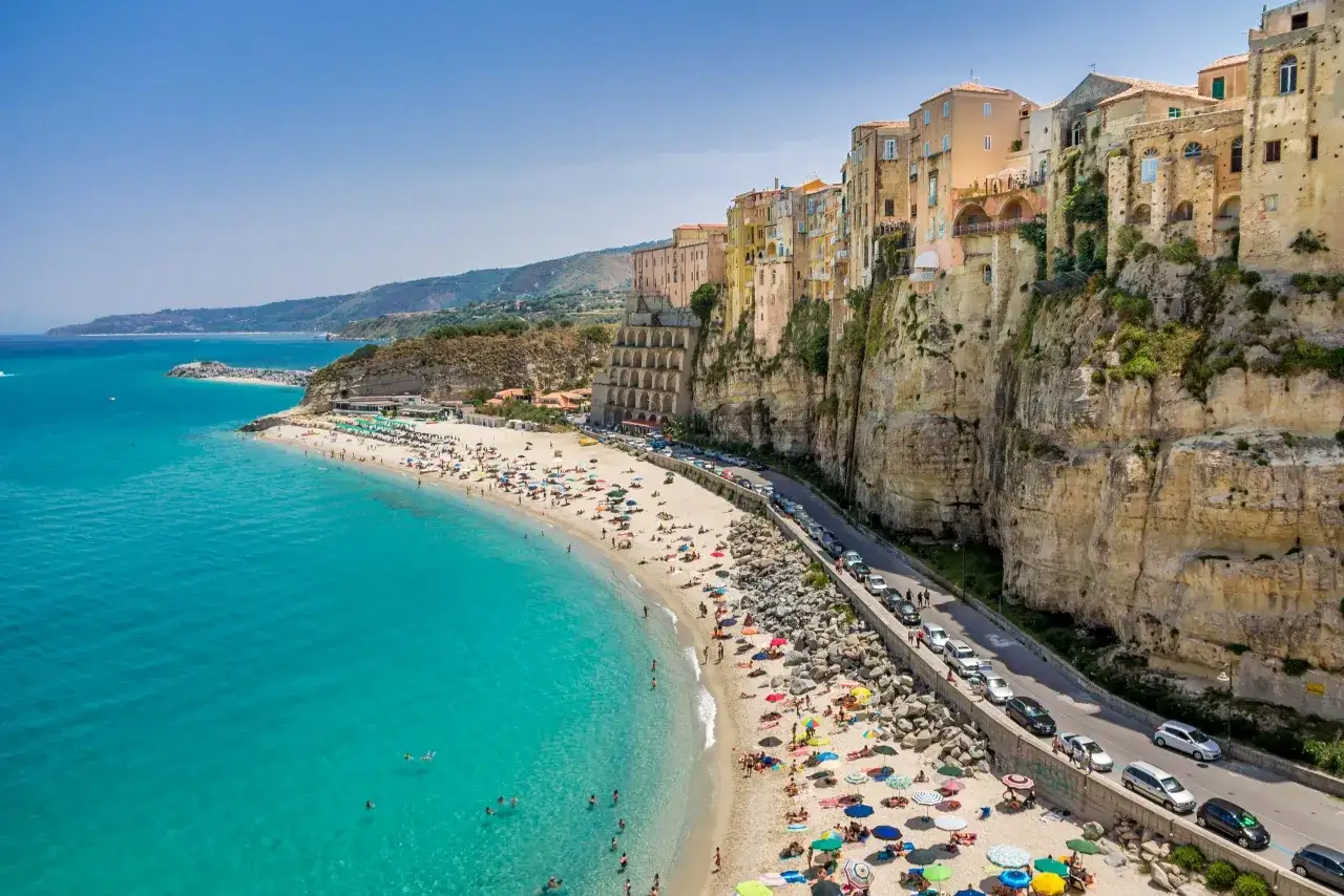 Tropea: malownicze miasteczko na klifie nad turkusowym morzem. Droga wzdłuż plaży z samochodami, jakby prowadziła prosto do lotniska.