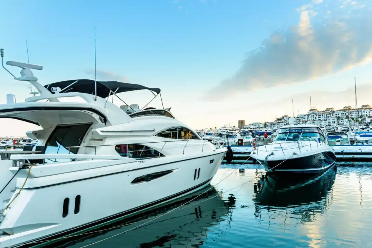 Luksusowe jachty cumują w słonecznym Puerto Banús, odbijając się w spokojnej wodzie.