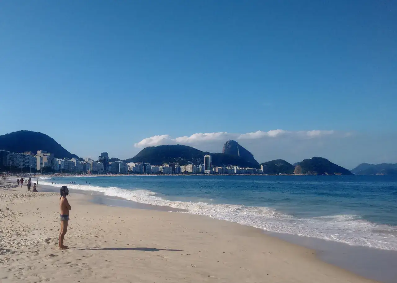 Plaża w Rio de Janeiro, z widokiem na miasto i góry. Czy Brazylia jest bezpieczna? Turyści odpoczywają, ciesząc się słońcem i oceanem.