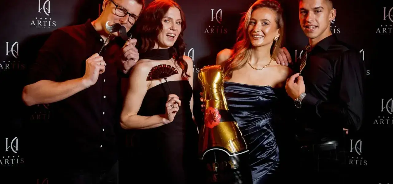 Grupa przyjaciół świętuje sylwestra w hotelu Artis. Trzymają balony w kształcie butelki szampana i rekwizyty do zdjęć.