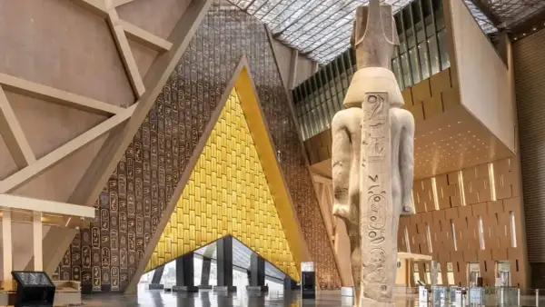 Wielki posąg faraona w nowoczesnym muzeum egipskim. Ściany zdobią hieroglify i złote panele.