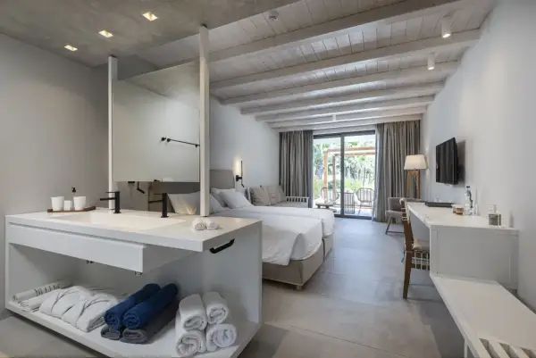 Pokój hotelowy z dwoma łóżkami, łazienką i widokiem na taras, idealny na pobyt w Caravia Beach Kos.