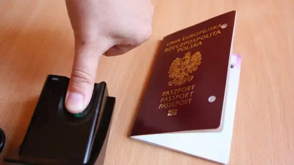 Palec na czytniku linii papilarnych obok polskiego paszportu. To pokazuje, ile ważny jest paszport w podróży.