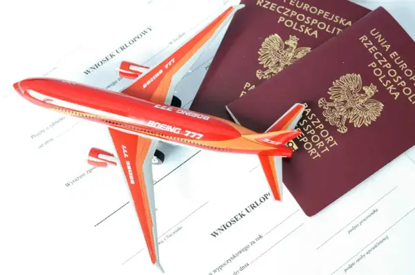Czerwony samolot i dwa polskie paszporty leżą na wniosku urlopowym. Czy do Albanii potrzebny jest paszport? Sprawdź przed podróżą!