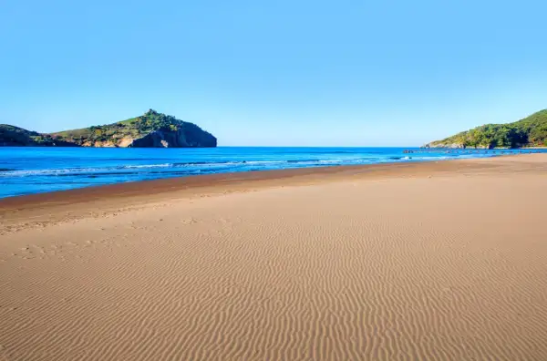 Piękna plaża w Sarigerme, z piaszczystym brzegiem i turkusowym morzem, w tle skaliste wzgórza.