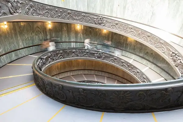 Watykańska, spiralna klatka schodowa z bogatymi zdobieniami, gdzie ludzie spieszą na audiencję u papieża.