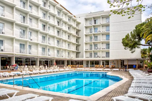 Basen i leżaki przy hotelu Don Juan Resort. Wiele białych balkonów hotelowych z widokiem na basen.