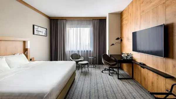 Nowoczesny pokój w jednym z **courtyard hotels Warsaw**. Duże łóżko, wygodne fotele i biurko przy oknie.