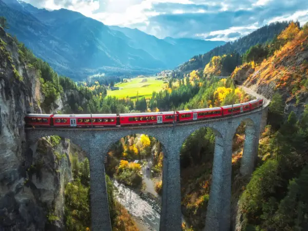 Czerwony pociąg Bernina Express przemierza malowniczy alpejski krajobraz jesienią. Sprawdź bernina express cena i zaplanuj podróż!