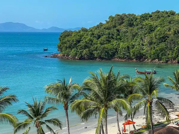 Rajska plaża Ao Nang z palmami, turkusową wodą i łodziami.