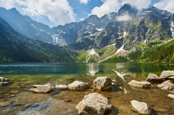 Piękna trasa nad Morskie Oko. Jezioro otoczone skalistymi szczytami Tatr, z zielonymi lasami i kamienistym brzegiem.