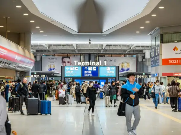 W Terminalu 1 lotniska ludzie z bagażami spieszą się, zastanawiając się, czy do Japonii potrzebna jest wiza.