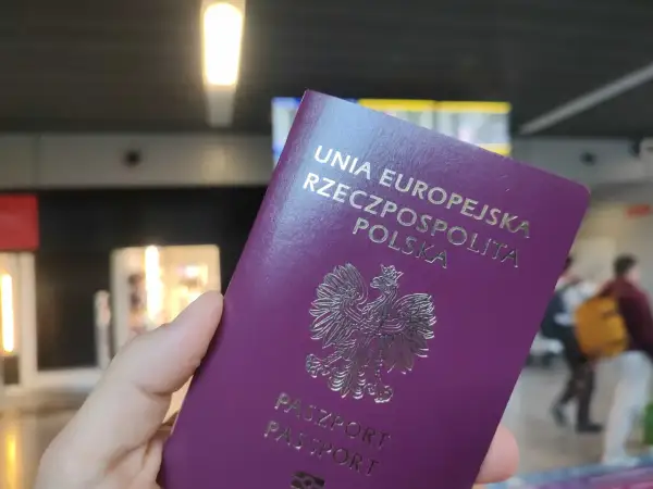 Polski paszport w dłoni, gotowy do podróży. Może to być początek drogi po wizę do Anglii.
